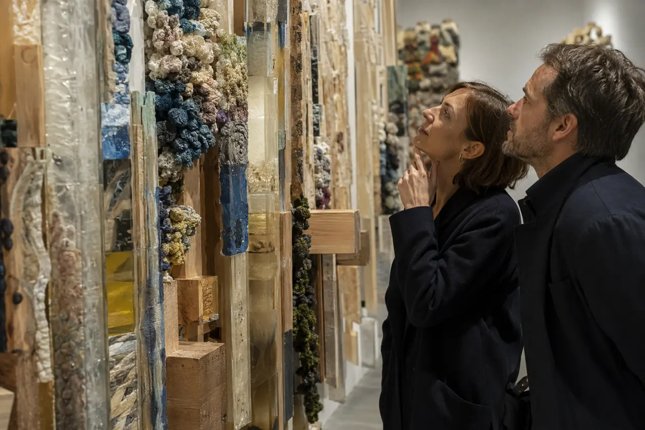 Visiteurs observant une œuvre contemporaine composée de textiles et de matières recyclées