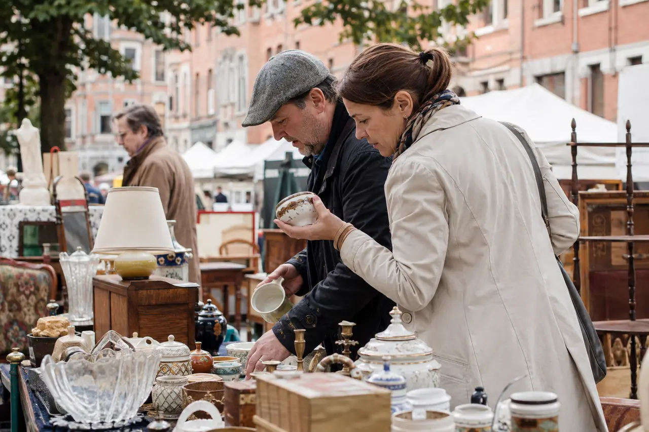 Adultes examinant de la vaisselle ancienne sur un stand de brocante à Lille