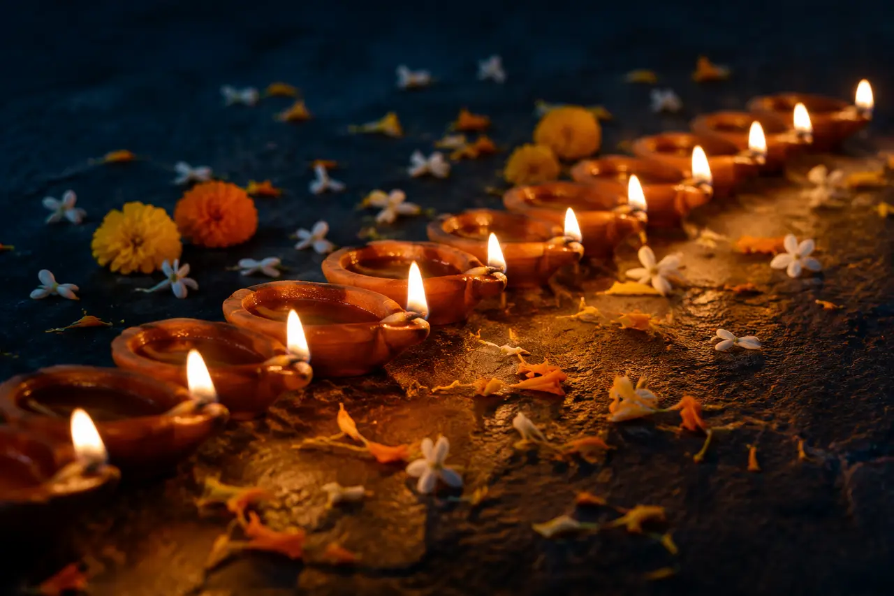 Rangée de lampes diyas en terre cuite entourée de pétales de fleurs