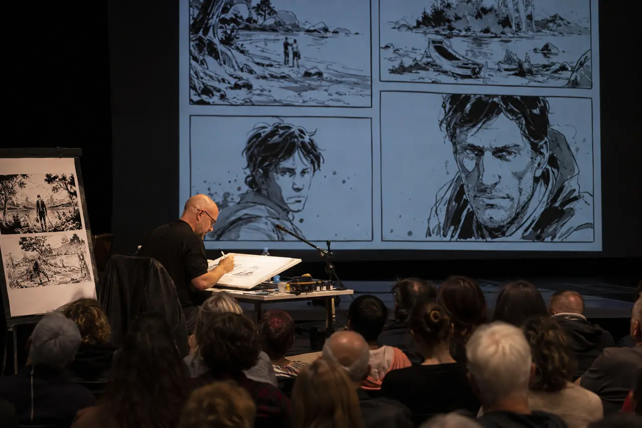 Auteur adulte réalisant une démonstration de dessin devant un public à Angoulême