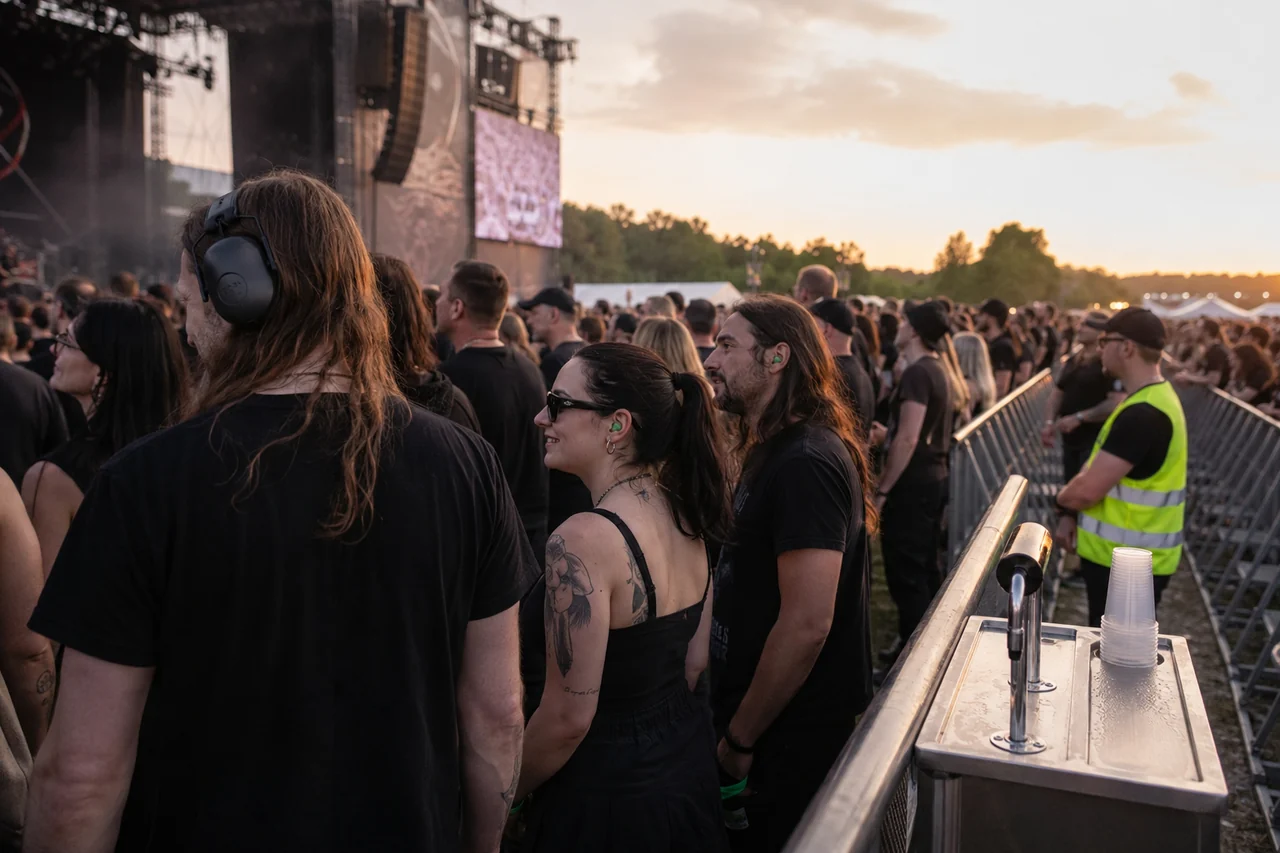 Festivaliers adultes avec protections auditives près d’un point d’eau et d’une zone de sécurité