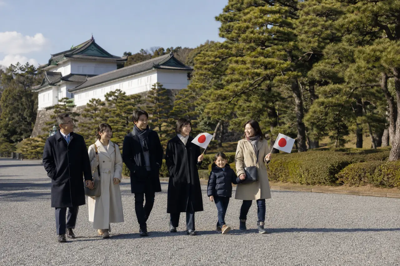 Six visiteurs marchant près du palais impérial avec des drapeaux japonais