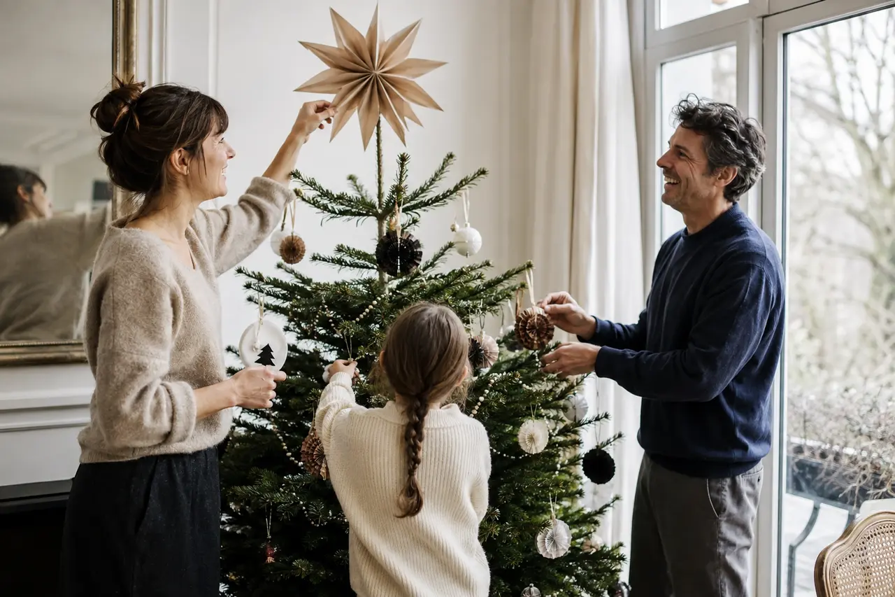 Parents et enfant décorant ensemble un sapin de Noël